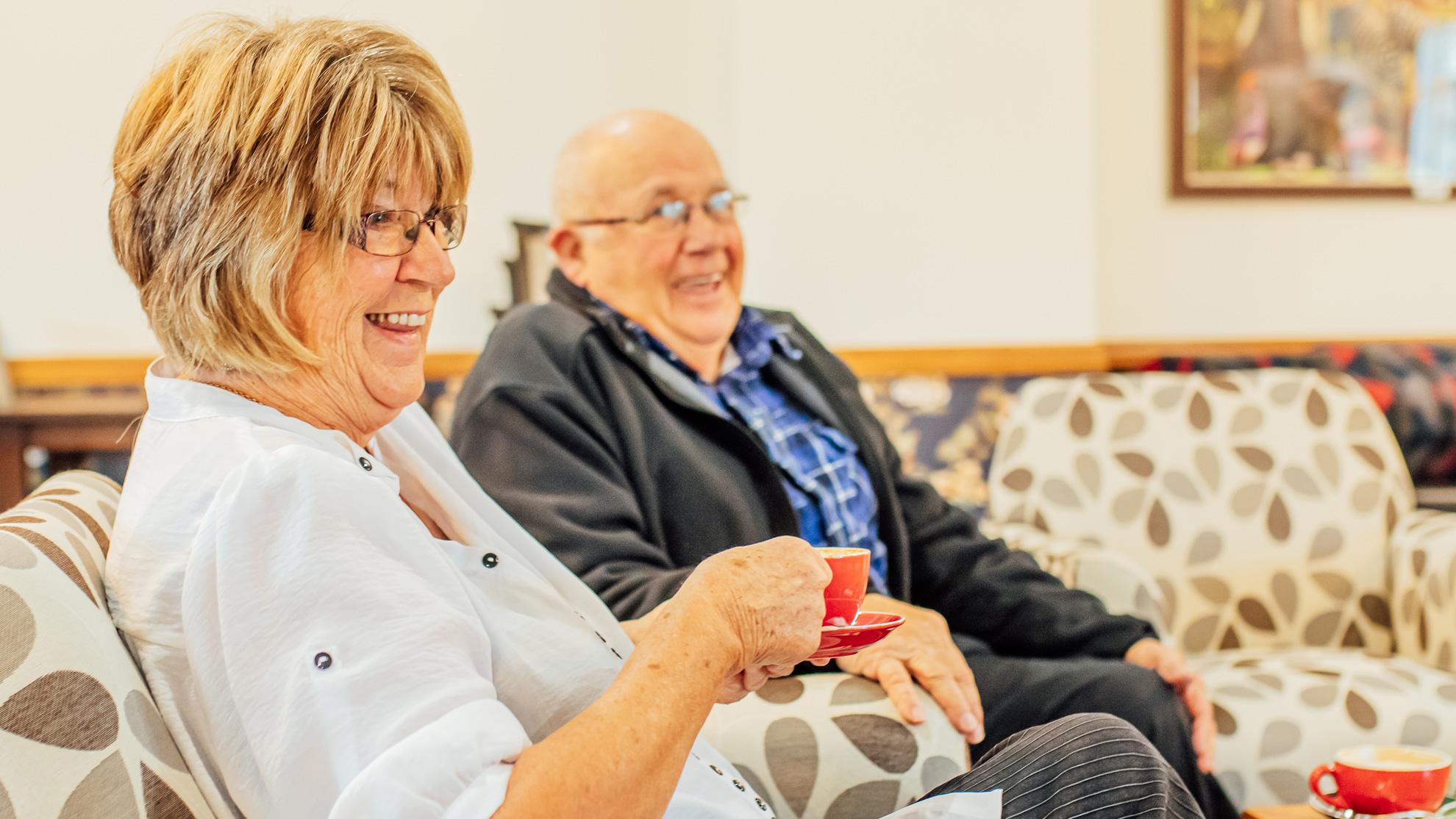 Group of residents drinking coffee around a table.